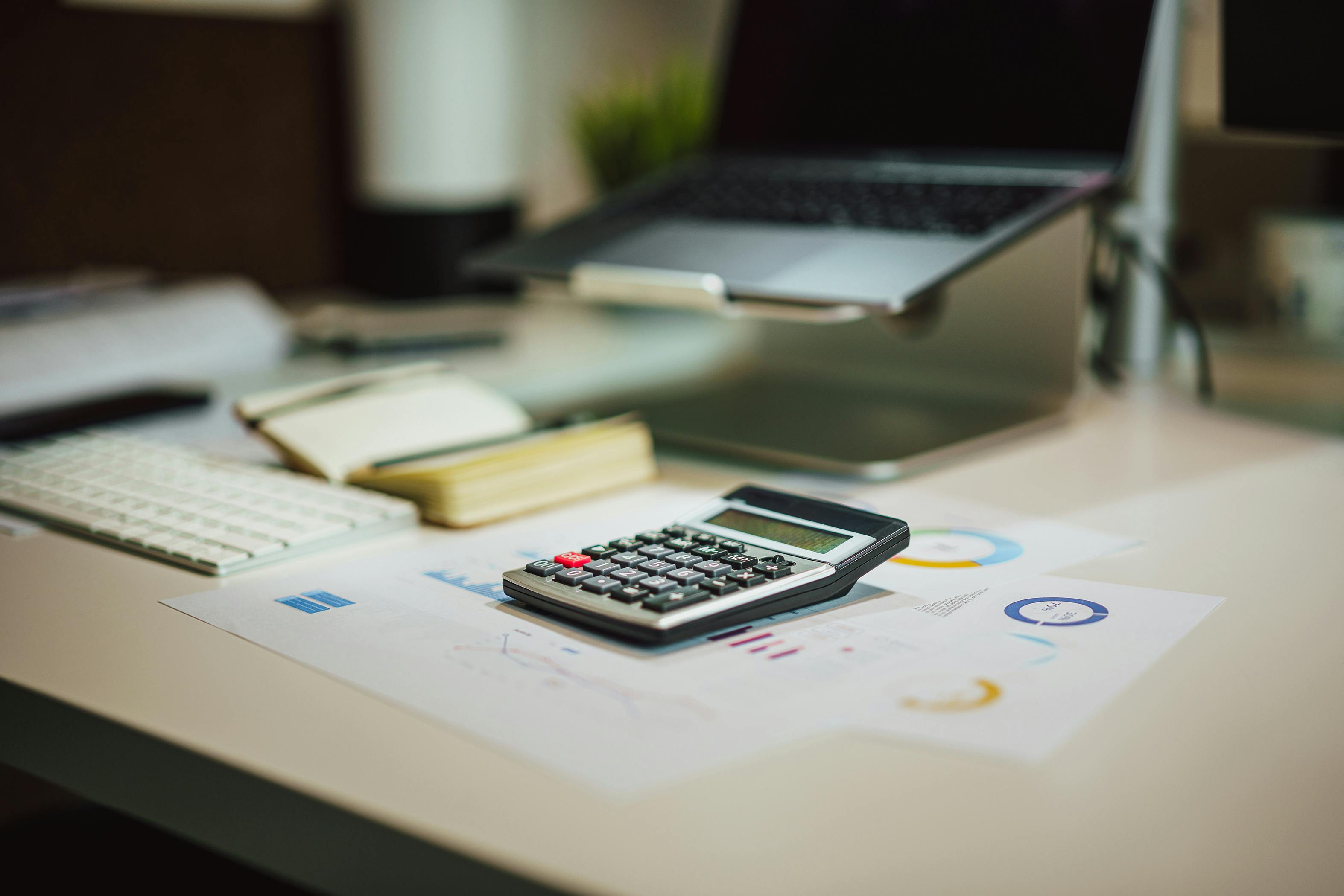 Professional bookkeeping workspace with laptop, calculator, and financial documents.